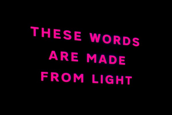 THESE WORDS ARE MADE FROM LIGHT projected onto a black wall